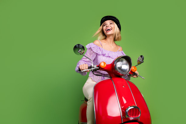 心情愉快的可爱女孩骑着滑板车，望向空旷的地方，背景为绿色。图片下载