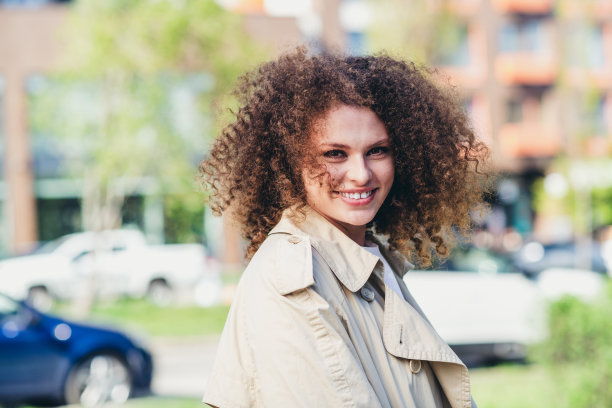 阳光明媚的春天户外，穿着时尚米色风衣的可爱女孩的照片图片下载