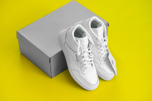 白色运动休闲鞋和鞋盒在黄色背景上图片下载