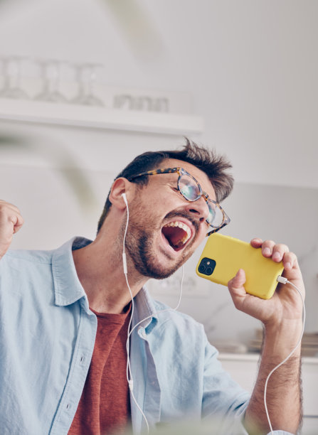 一个快乐的男人戴着耳机，享受着来自智能手机的音乐图片下载