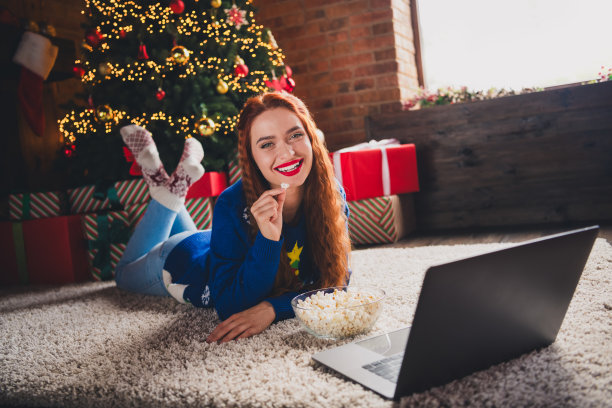 可爱的女孩穿着时尚的蓝色毛衣，躺在地毯上，在舒适的室内客厅观看电影。图片下载