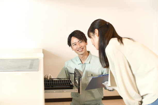 一名男性工人在检查厨房烤架，一位年轻女性在旁观察。图片下载