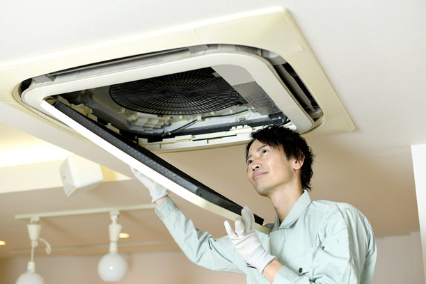 亚洲男性工人在检查天花板安装的空调图片下载