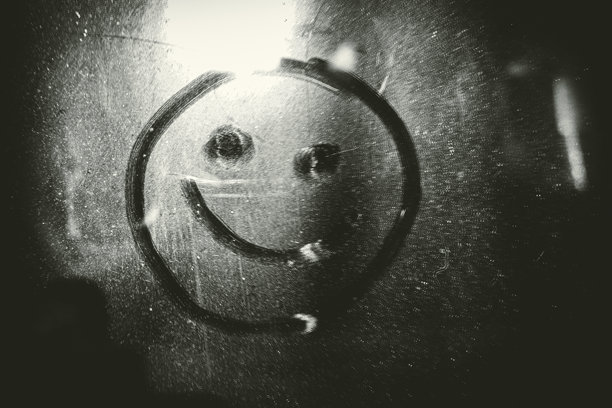 用手指在尘土覆盖的玻璃上画一个微笑图标图片下载