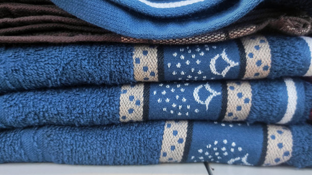 堆叠的彩色毛巾，带有图案设计，展示在商店货架上，展现其柔软的质地和精致的细节。非常适合家庭使用或作为礼物。图片下载