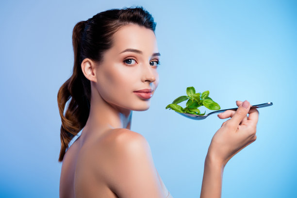 漂亮女士吃绿色叶子植物照片，蓝色背景图片下载