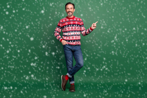 成熟快乐的男人微笑着，指向绿色背景上空白的地方，展示促销消息的全身照片图片下载