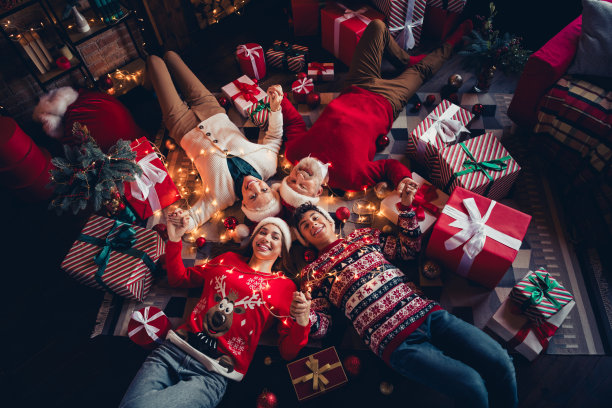 从上方拍摄的照片，展示了一家人——孙子、孙女、祖母和祖父在家中躺着，手牵手享受新年的温馨时光。图片下载