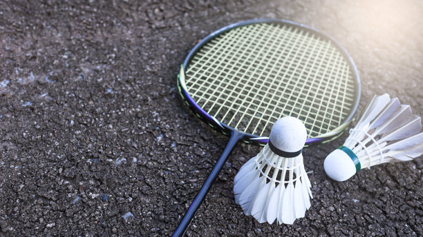 黑色土壤背景上的羽毛球和球拍，象征着运动精神和全球竞争，体现了体育的本质和追求卓越的精神。图片下载