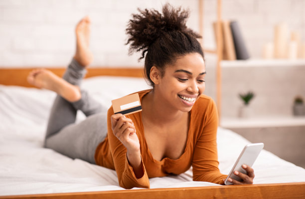 女孩在室内床上使用智能手机和信用卡图片下载