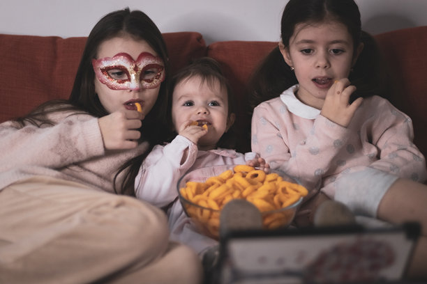 三个女孩坐在沙发上看电影。图片下载