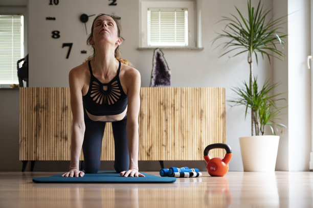 年轻女性穿着运动服，伸展身体并弓起背部图片下载