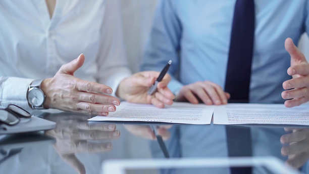 多元化的商务人士在签署合同文件前进行讨论。律师团队在办公室的玻璃桌前工作。图片下载