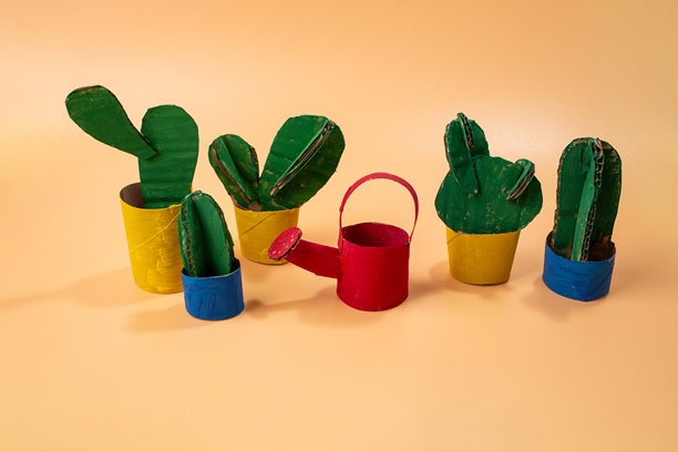 一组仙人掌植物排列在黄色画布上。概念艺术玩具设计。儿童纸板剪影浇水壶的产品照片。图片下载