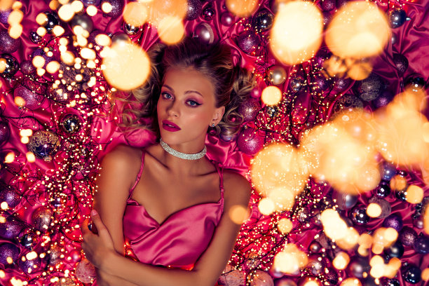 奢华女士在纹理背景上摆姿势，背景装饰着圣诞闪光球的高角度照片图片下载