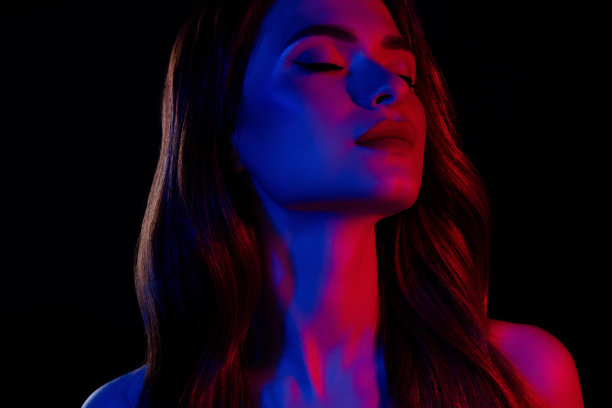 在黑暗的霓虹多彩背景下，闭着眼睛感到孤独的漂亮女孩照片图片下载