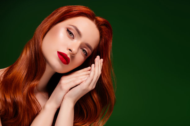 迷人漂亮女孩的照片，手触碰着，长发闪亮，背景为绿色。图片下载