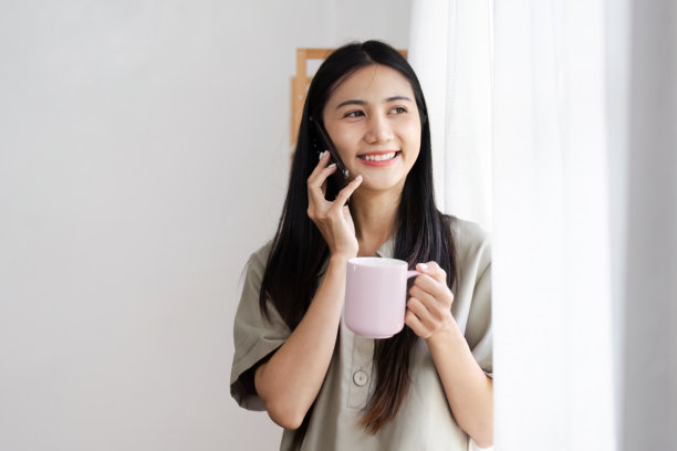 年轻女性早晨使用手机并喝咖啡 - 现代科技与生活方式概念图片下载