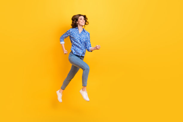 充满活力的女孩在黄色背景上跳跃奔跑的全身侧面肖像图片下载