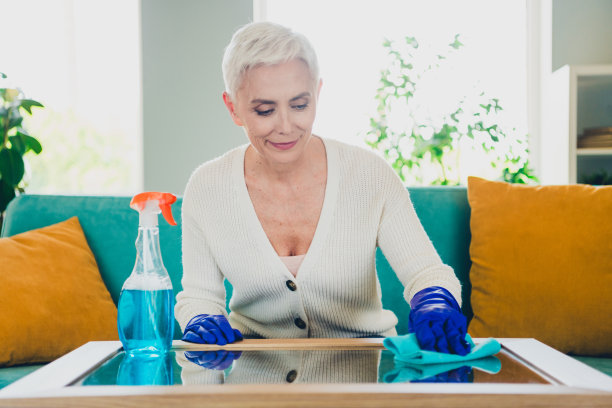 可爱的退休妇女在客厅里擦拭桌子玻璃的照片图片下载