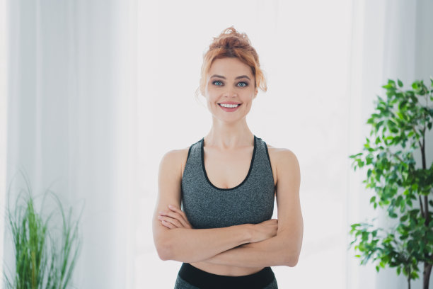 穿着运动服、双手交叉的迷人运动型健康女性室内照片图片下载