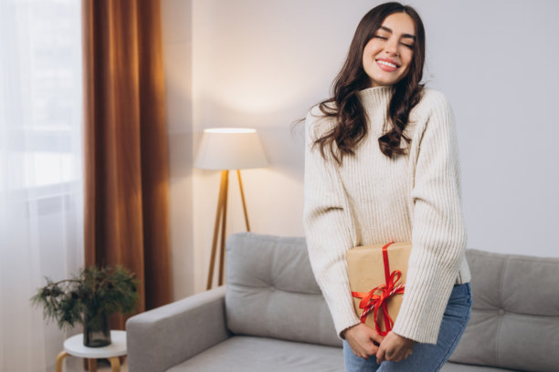 美丽快乐的女人在家中拿着或拆开新年或圣诞礼物图片下载