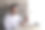 一个男人坐在桌子前，面前有一台笔记本电脑和一部手机。他面带微笑，正在看着他的手机。图片下载