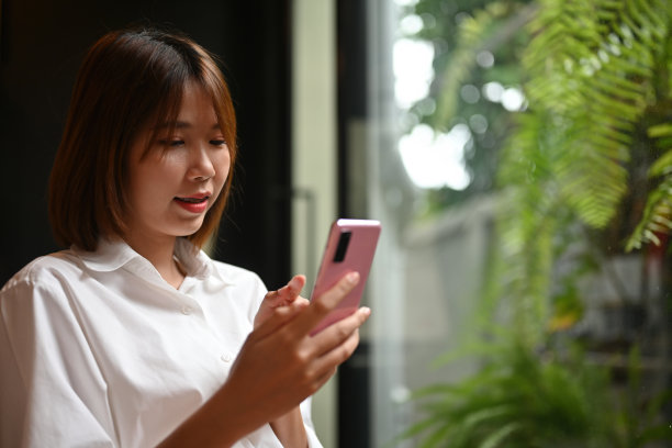 坐在窗边的亚洲短发女性近距离看智能手机的照片图片下载