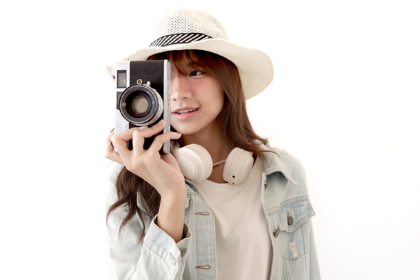 穿着牛仔夹克和夏季帽子的亚洲年轻女性旅行者，手持胶卷相机准备拍摄一张令人印象深刻的照片。背景中是一位年轻女性游客与她的经典老式胶卷相机。旅行女孩带着相机前往她的目的地。图片下载
