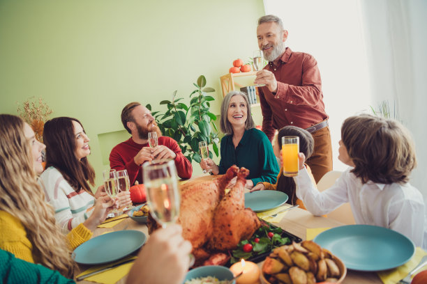 一个快乐的大家庭在室内房间的家里庆祝感恩节，坐着吃喝的照片图片下载