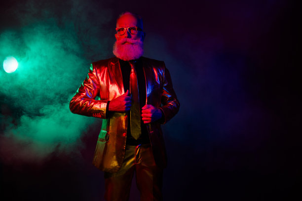 奢华的吸引人男艺人在黑暗霓虹色背景下的豪华VIP俱乐部中站立的照片图片下载