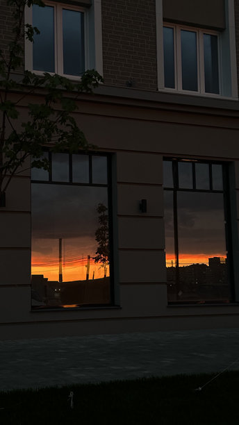 城市住宅楼窗户中映射出的明亮美丽的日落，手机拍摄的照片图片下载