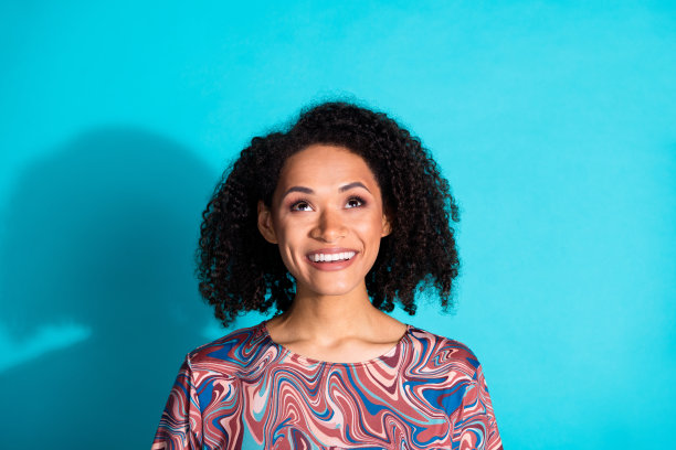 漂亮年轻女孩的照片肖像，仰望空旷的空间，穿着时尚多彩的衣服，背景为水绿色。图片下载