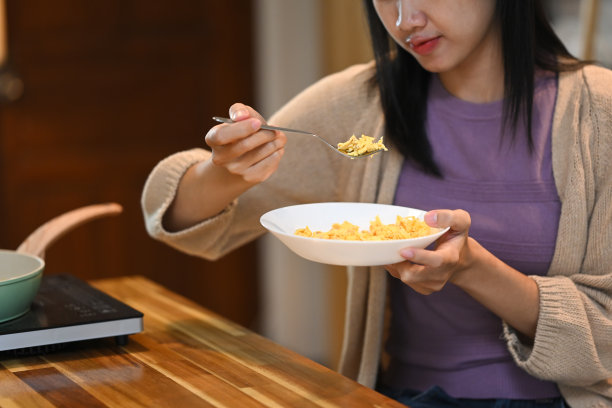 女人坐在木制厨房柜台旁，用叉子吃炒鸡蛋的局部照片图片下载