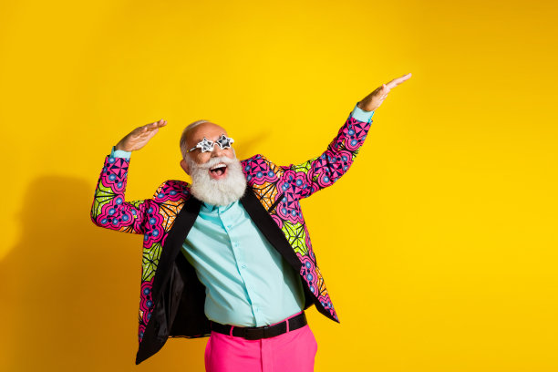 穿着鲜艳西装的疯狂快乐男人在黄色背景下的空旷空间中跳舞的照片图片下载