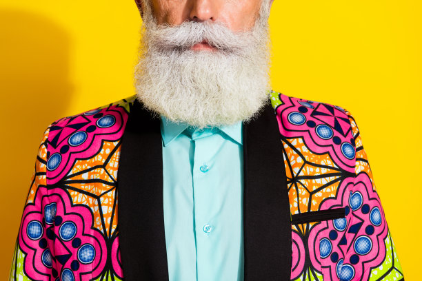 时尚的胡须老年绅士在理发店的裁剪照片，穿着色彩鲜艳的优雅服装，背景为黄色。图片下载