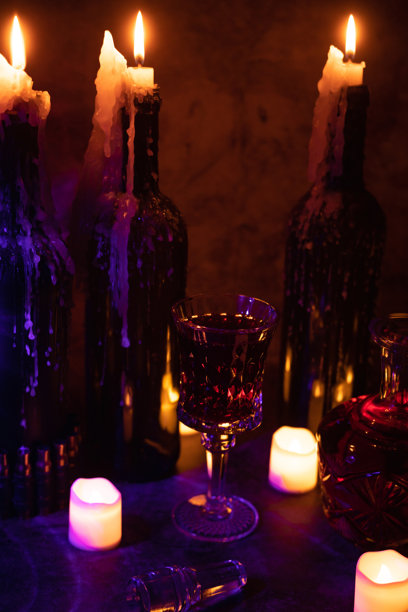 一杯红酒，一个古老的水晶酒壶，放在点燃蜡烛的桌子上。昏暗的照片。图片下载