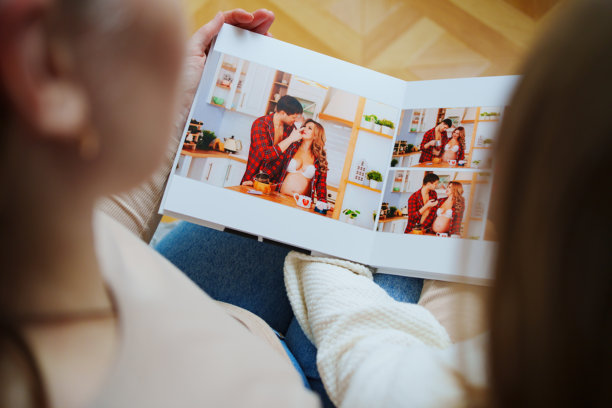 母亲和女儿翻阅一本有爸爸和怀孕妈妈照片的书。图片下载