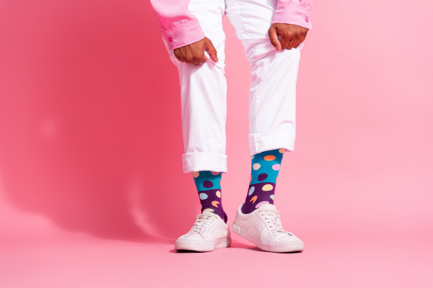 年轻男子穿着有趣的点点圣诞袜，背景为粉色，照片经过裁剪。图片下载