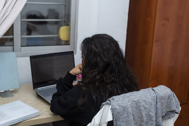 年轻女性在卧室里背对镜头，正在用笔记本电脑阅读文本的照片图片下载