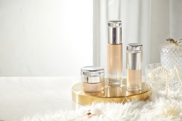 一张用于推广美容产品的图片，展示了一个罐子和两个没有标签的瓶子，放置在一个铜托盘上，周围有一块毛皮地毯，玻璃瓶上缠绕着珍珠串。图片下载