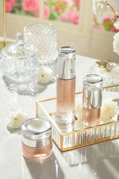 三款透明土色粉色渐变的产品在一个玻璃托盘上展示，旁边有玻璃瓶和装饰品，背景时尚，照片采用高角度拍摄。图片下载