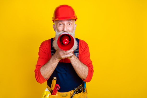 退休技师工匠手持扩音器在明亮的彩色背景上传播维修促销信息的照片图片下载