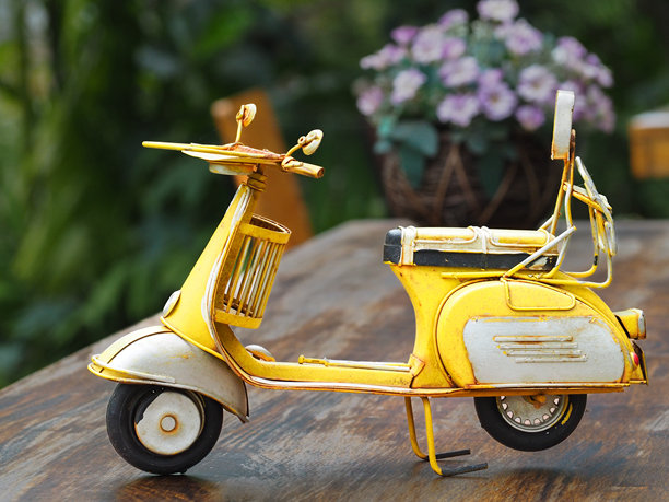 一辆由金属制成的鲜艳黄色经典复古玩具摩托车的照片。图片下载