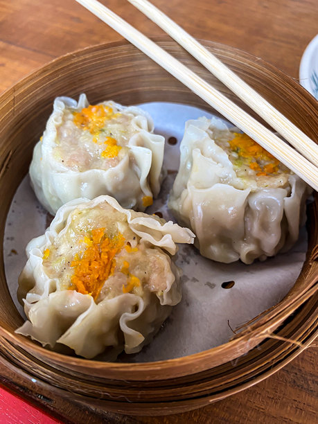 蒸虾烧卖特写照片，装在竹蒸笼中。用筷子吃蒸饺点心。正宗的典型中国美食。图片下载