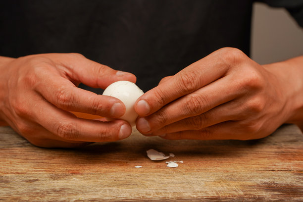 运动员的食物。准备食物。横向照片。素食。男人在木板上拿着鸡蛋。煮鸡蛋。剥壳清理鸡蛋，特写。健康食品。蛋白质。图片下载