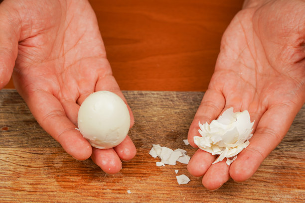 男人手持鸡蛋在木板上。煮鸡蛋。剥壳后的干净鸡蛋，特写。健康食品。蛋白质。运动员的食物。准备食物。横向照片。素食者。图片下载