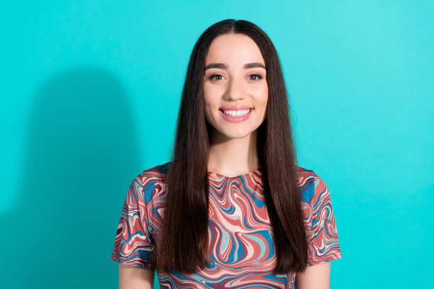 照片中妩媚少女的女子穿着印花衬衫微笑着，空白空间孤立的绿松石色背景图片下载