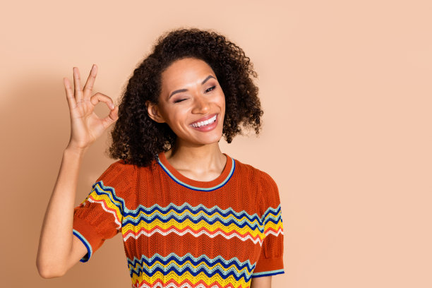 照片中的好心情的女人烫发的头发，穿着针织t恤，显示ok批准的好工作孤立的米色背景图片下载