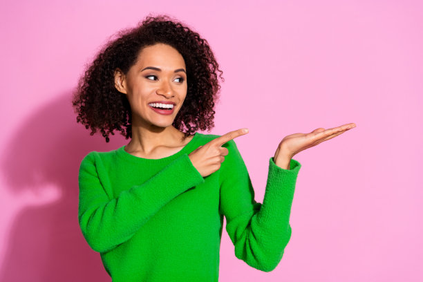 照片中迷人可爱的女人穿着绿色时尚的衣服，推荐在粉红色的背景上孤立的空白空间图片下载